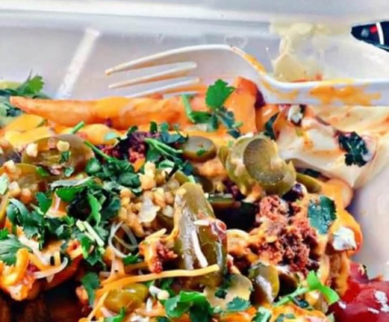 Pastor fries under cheese, meat, jalapenos and crema. Photograph posted by Pumbah's Tacos & Burgers.