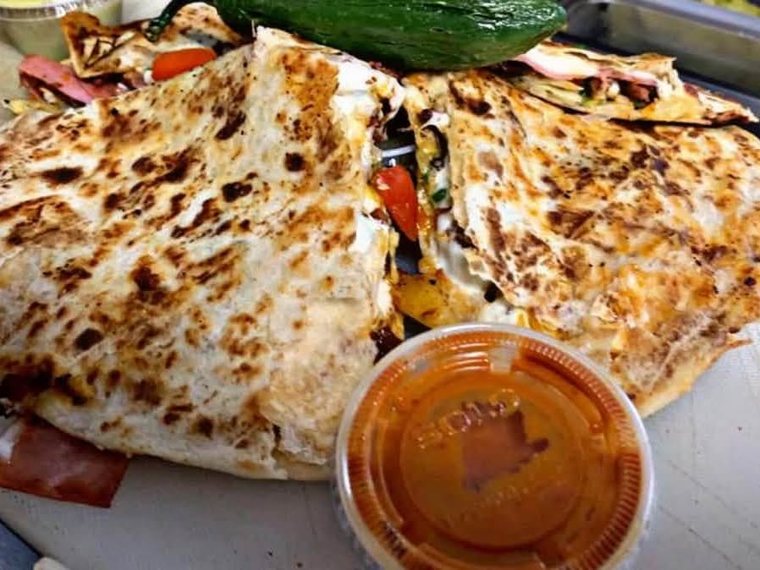 The Pumbah Quesa, a folded quesadilla browned on the griddle, with a cup of salsa. Photograph posted by Pumbah's Tacos & Burgers.