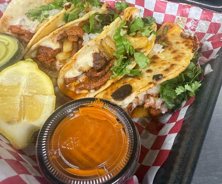 Queso tacos de pastor with cilantro, lemon and a cup of salsa. Photograph posted by Pumbah's Tacos & Burgers.